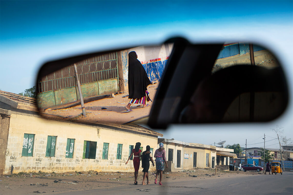 A Muslim woman is reflected in a car mirror while Christian women are seen walking down the street in Kano, Nigeria, on March 31, 2013.<p>Courtesy VII Photo Agency / © Ed Kashi</p>