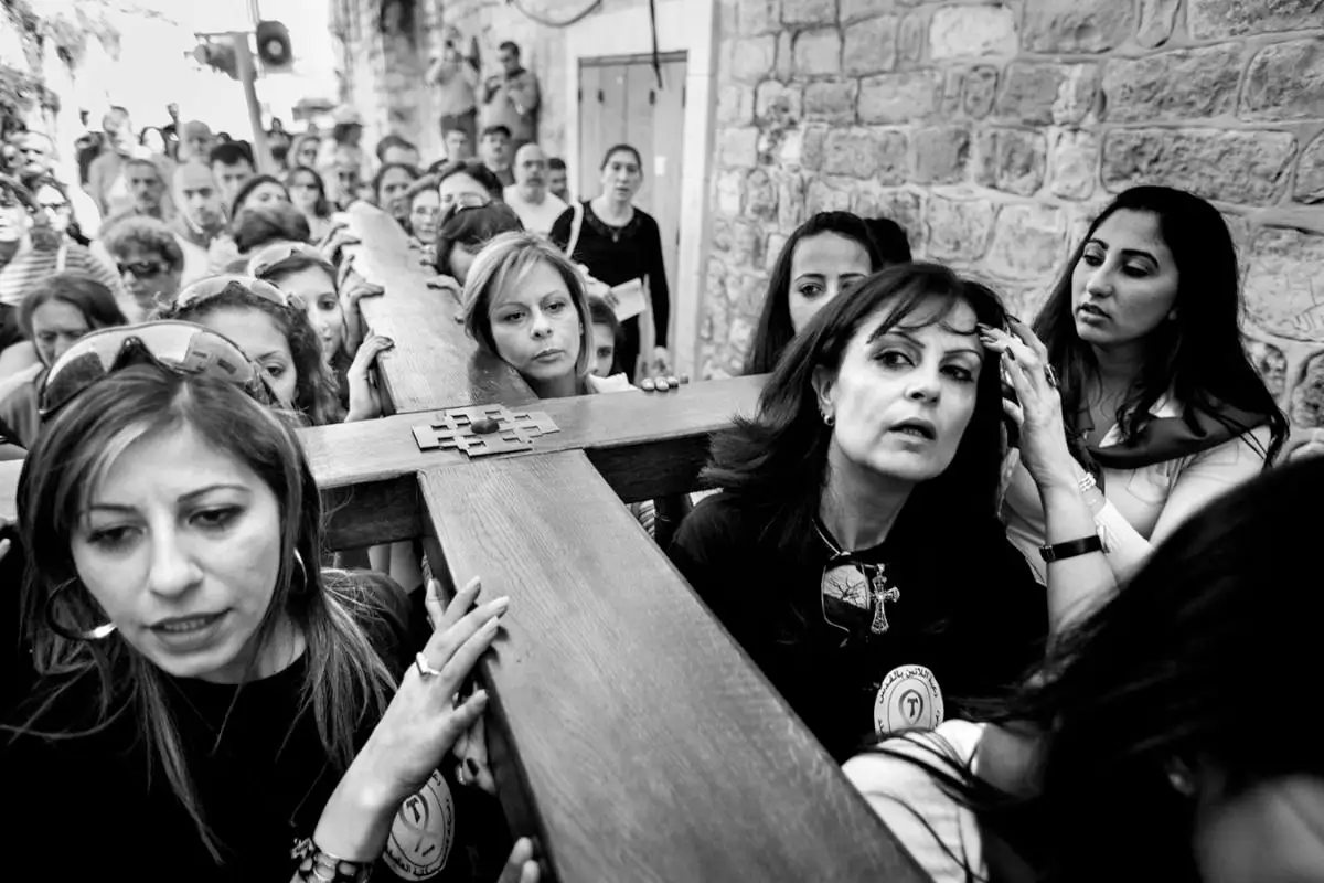 black and white photograph of women carrying a large wood cross in a procession