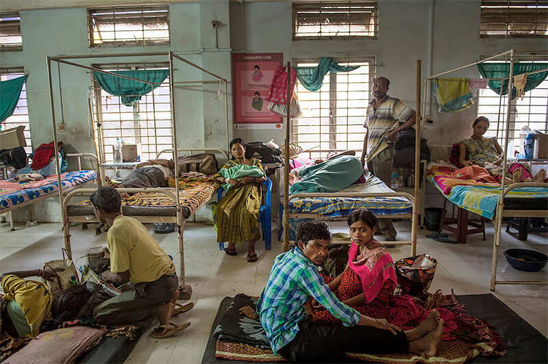 Lynsey Addario><p class=f12 l16 pt5 right>Indian families rest in a ward reserved for women recovering from cesarean sections, at Tezpur Civil Hospital. Assam has the highest rate of maternal mortality in India. Many public medical facilities are overcrowded and unhygienic, suffer from a chronic shortage of doctors, and often have patients sprawled on floors and in hallways. Tezpur, Assam, India. April, 2015.<br