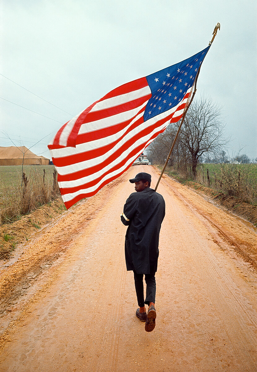 Henry Do-Right marching with the American Flag during the Selma to Montgomery March, 21 March 1965<p>© Dan Budnik</p>