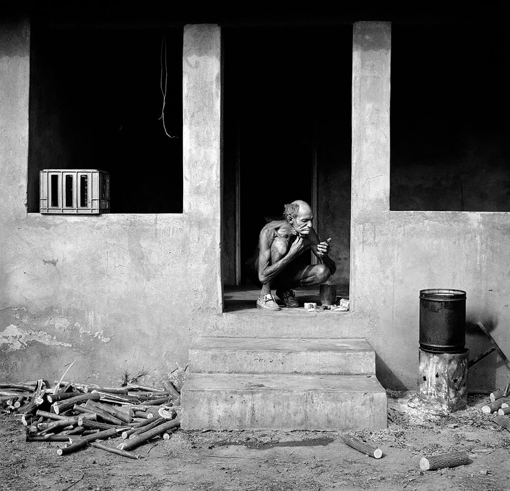 Man shaving on veranda Western TVL, 1986<p>© Roger Ballen</p>