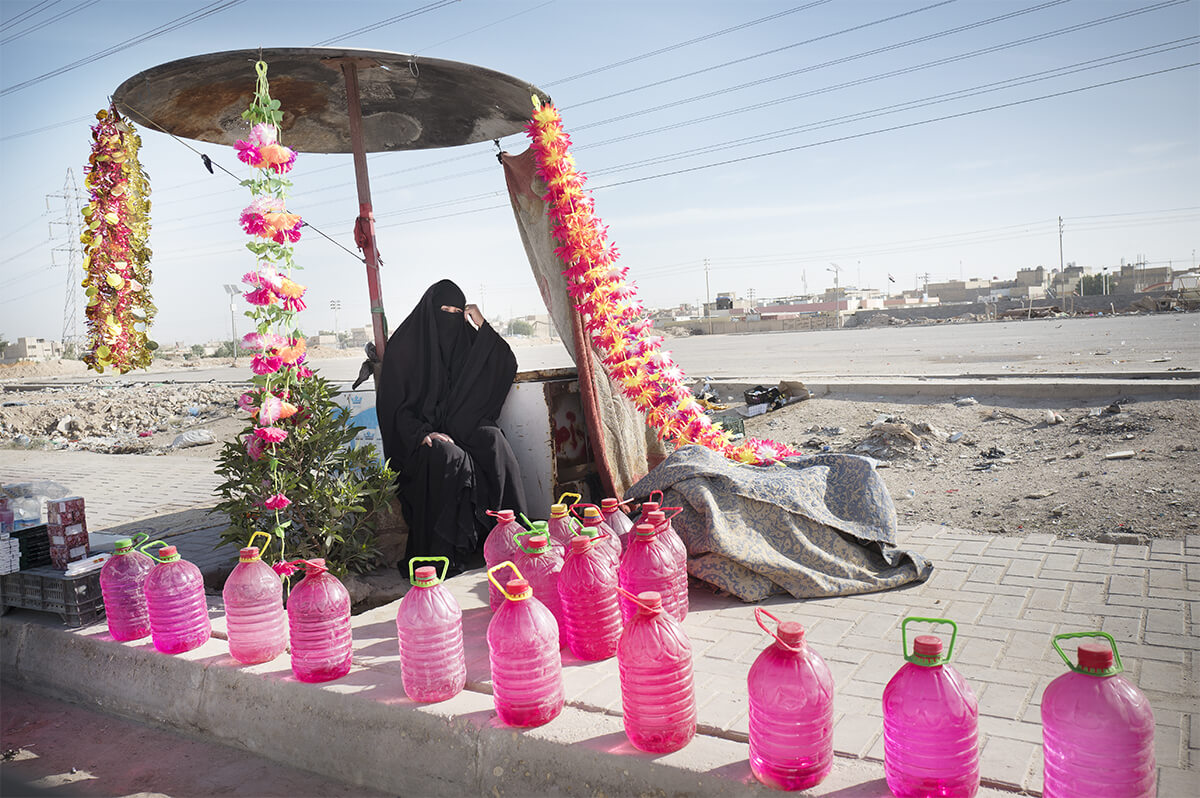 Une femme devant la nécropole de Najaf vend de l’eau de rose pour arroser et honorer les morts.<p>© Veronique De Viguerie</p>