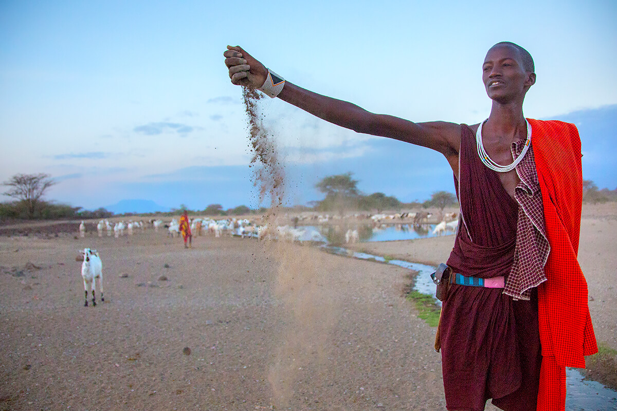 20 year old Masai Serem checks the dawn soil moisture while his lifestock drink the Embirika water point, 2014.<p>© Georgina Goodwin</p>