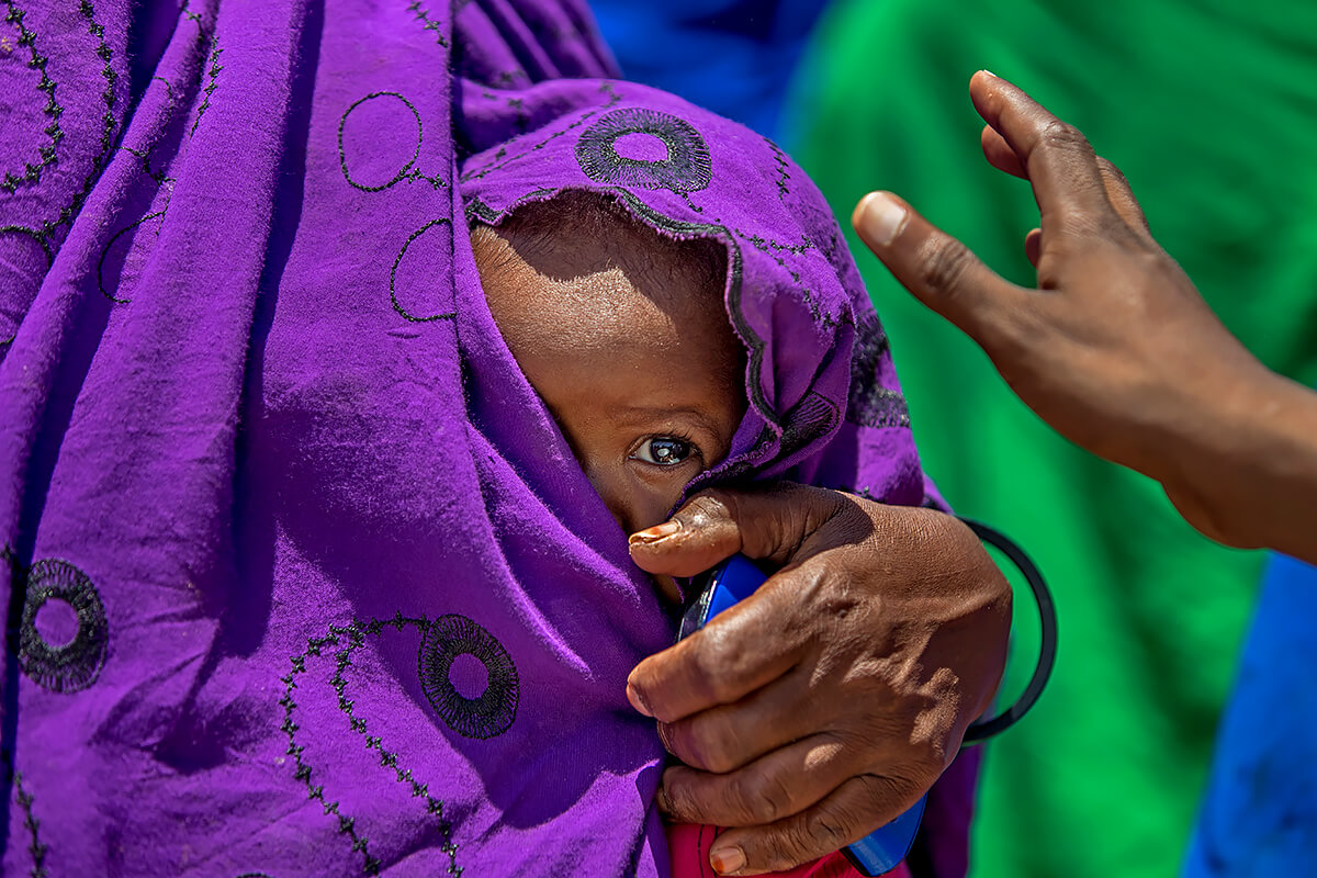 Peering through the folds in her mother’s dress was this beautiful girl in a makeshift camp in central Somaliland<p>© Georgina Goodwin</p>