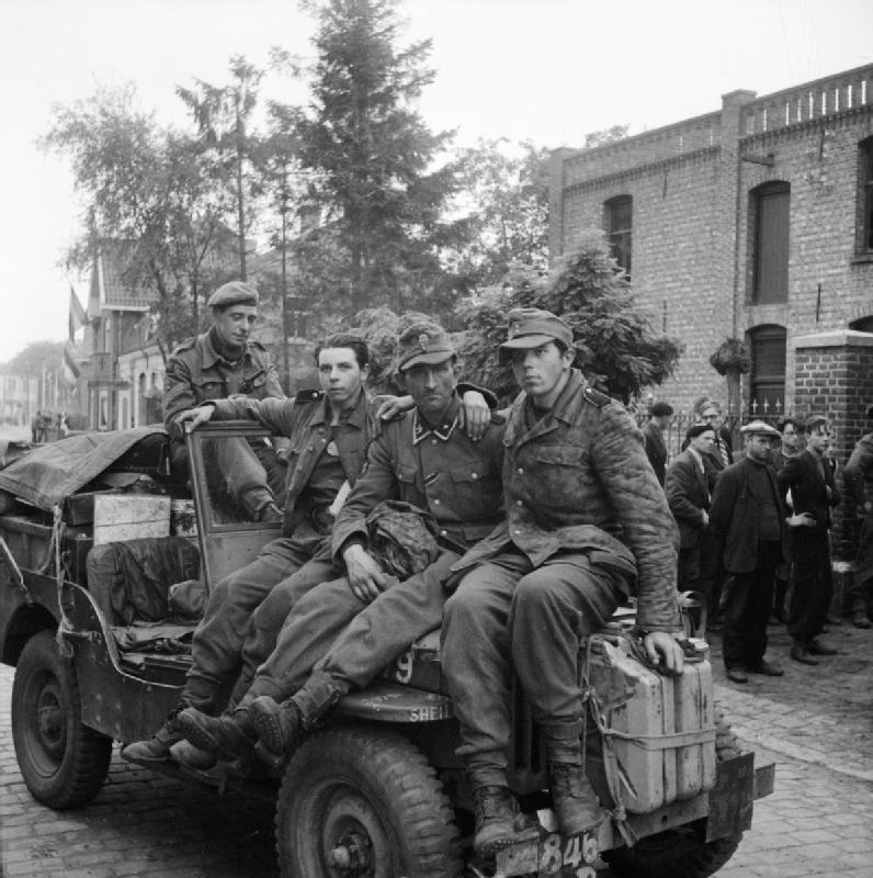 Three German prisoners are brought in on the bonnet of an Army Film and Photographic Unit jeep by Sgt Bert Hardy<p>© Bert Hardy</p>