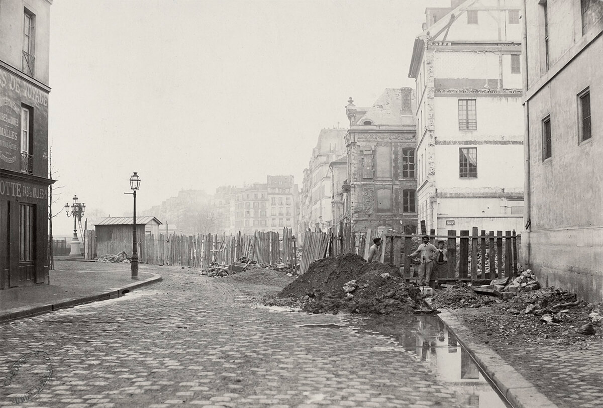 Looking along the beginning of Boulevard Henri IV, workmen standing in front of delapidated picket fence, builders rubble on edge of cobbled street, c<p>© Charles Marville</p>