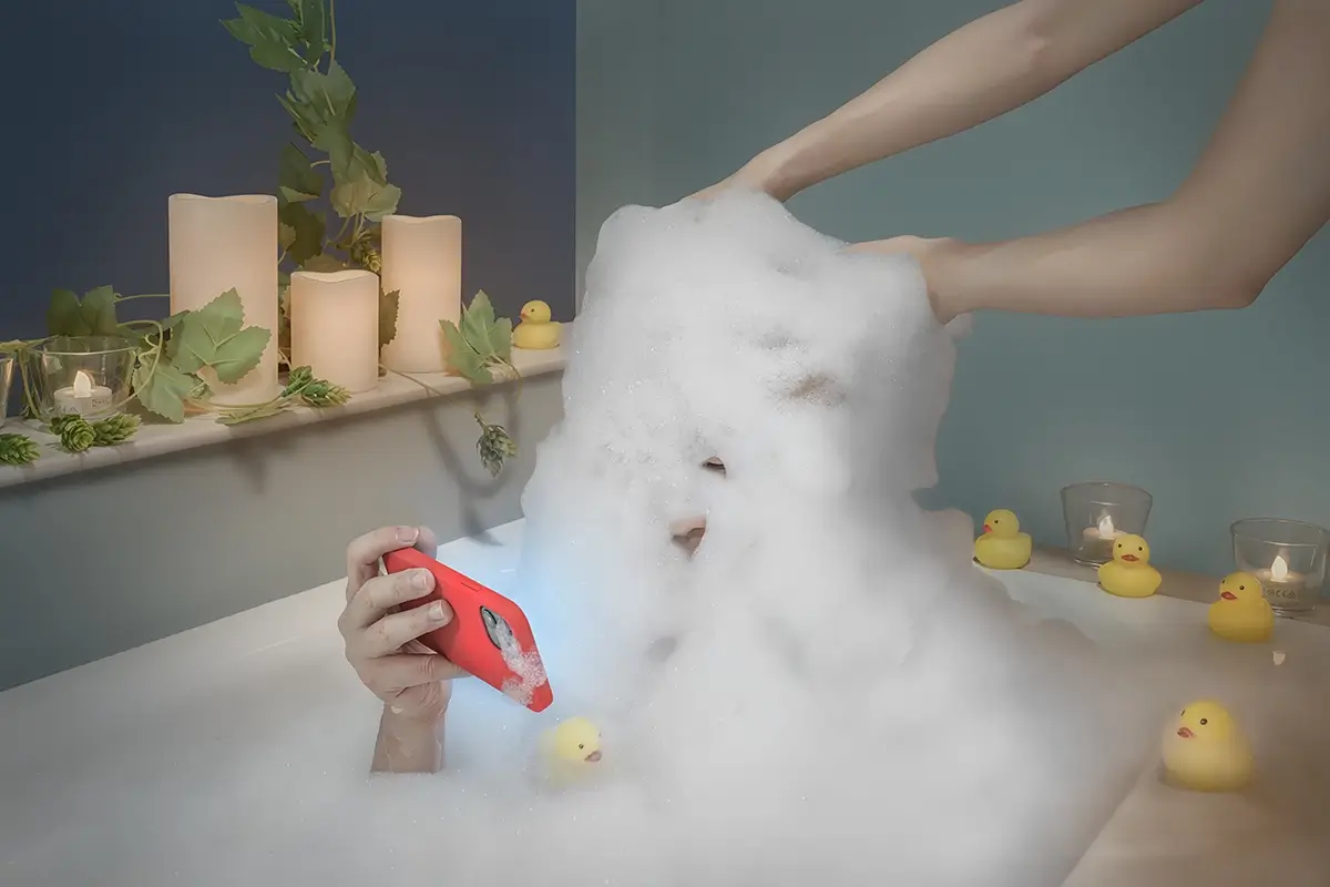 Foam Man: She bathes him while he scrolls—tender, absurd, unseen.<p>© Kantaya New</p>