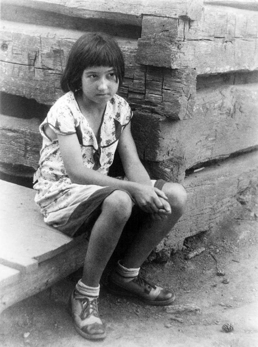 Small girl seated by log cabin, no. 1, circa 1930<p>© Doris Ulmann</p>