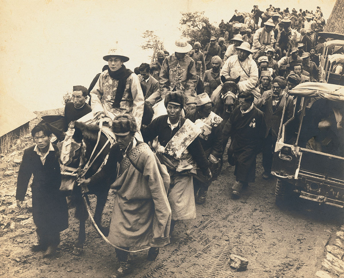 The Dalai Lama in ceremonial dress enters India through a high mountain pass, Sikkim, 1956<p>© Homai Vyarawalla</p>