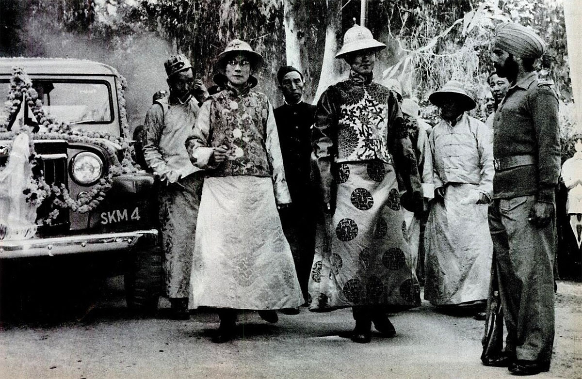 Wearing gold brocade gowns and jeweled gold hats the Dalai Lama (left) and Panchen Lama stand by garlanded auto sent to meet them, 1956<p>© Homai Vyarawalla</p>